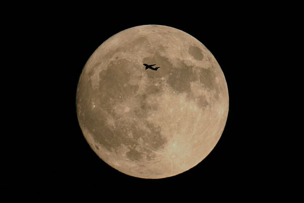 This plane flew near the horizon in front of full moon